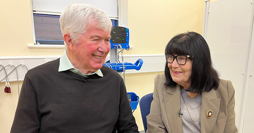Nigel and Heather looking towards each other and smiling in clinic